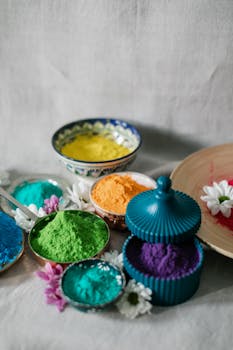 Vibrant Holi powders in various bowls, surrounded by flowers, perfect for festival celebrations.