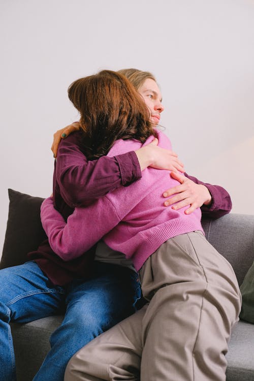 Young romantic couple in casual clothes sitting on comfortable sofa and hugging at home