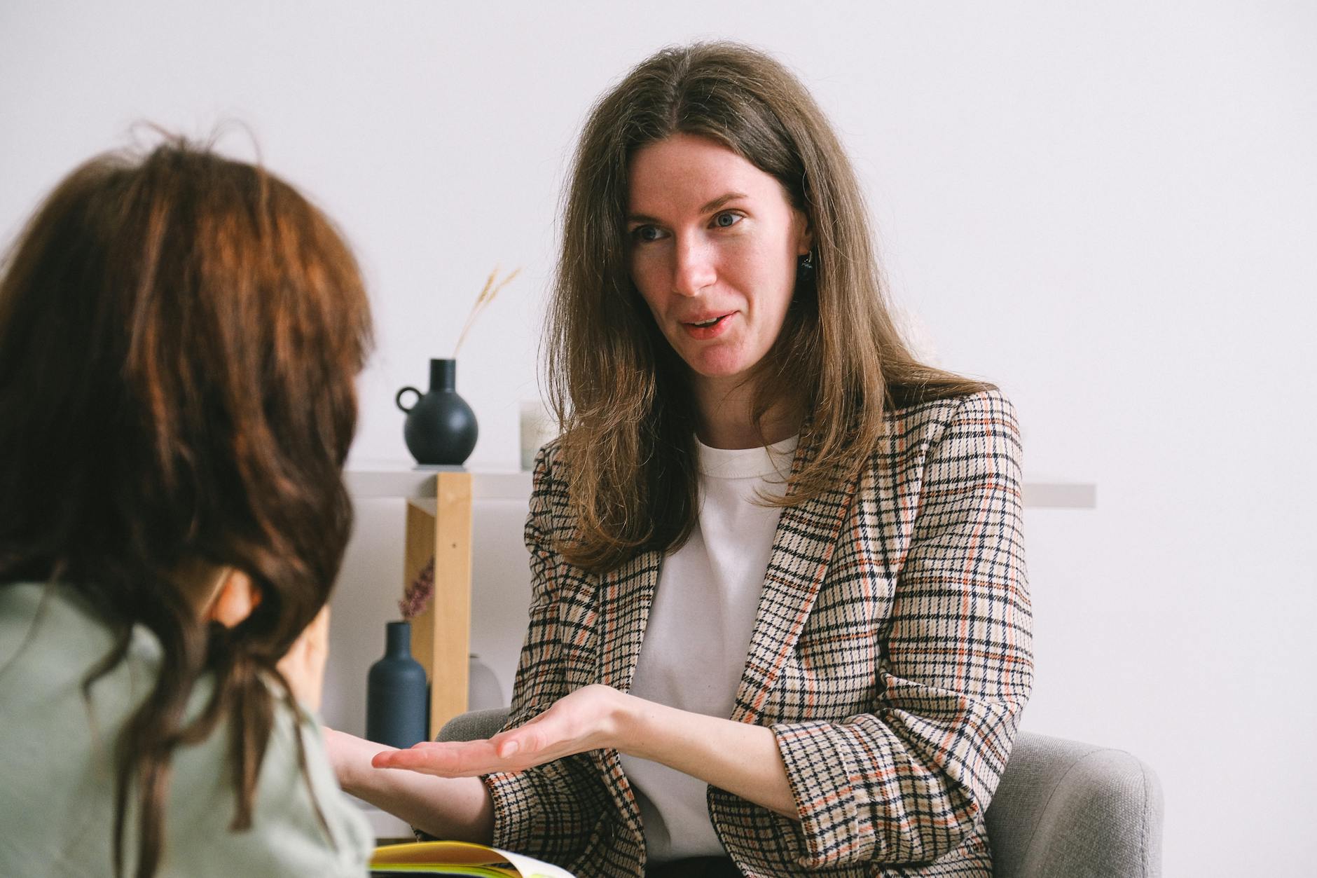 Smiling therapist speaking with anonymous female patient in light office