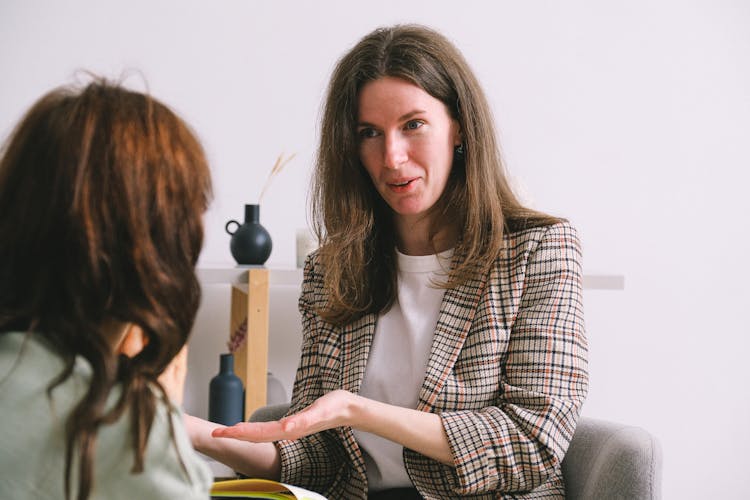 Smiling Therapist Speaking With Anonymous Female Patient In Light Office