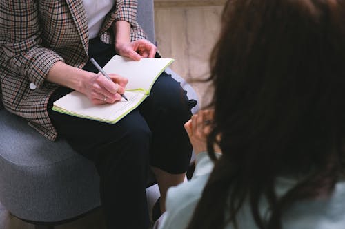 Free Crop counselor writing in diary while talking to patient Stock Photo