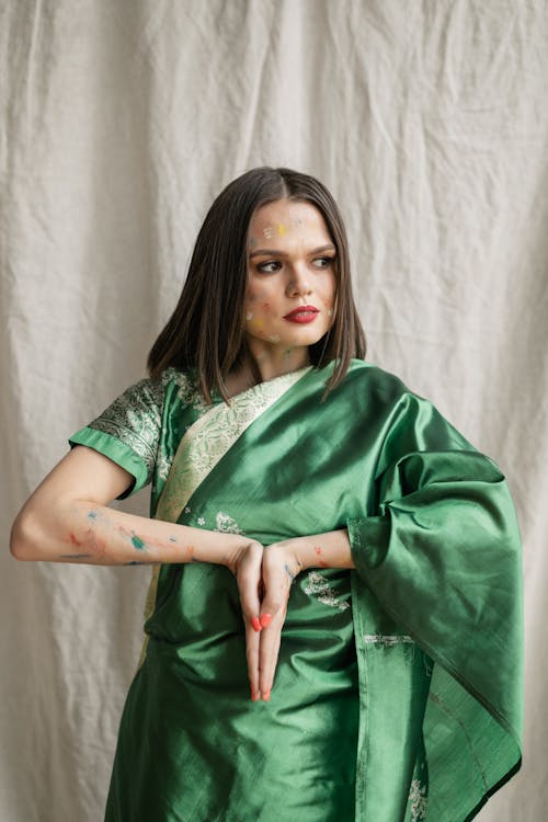 Woman in Green Sari Dress and Paints Stains on Face Holding Palms Together