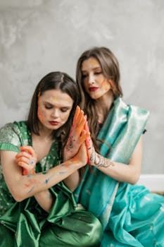Indian women celebrating Holi indoors with colorful powder and traditional attire, symbolizing friendship and joy.