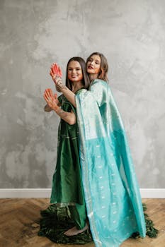 Two women celebrating Holi festival indoors with vibrant colors and traditional attire.