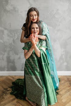 Two women in traditional attire celebrate Holi with vibrant colors and smiles.
