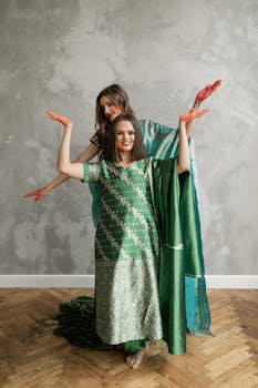 Two women dancing joyfully in traditional Indian attire during a vibrant festival celebration.