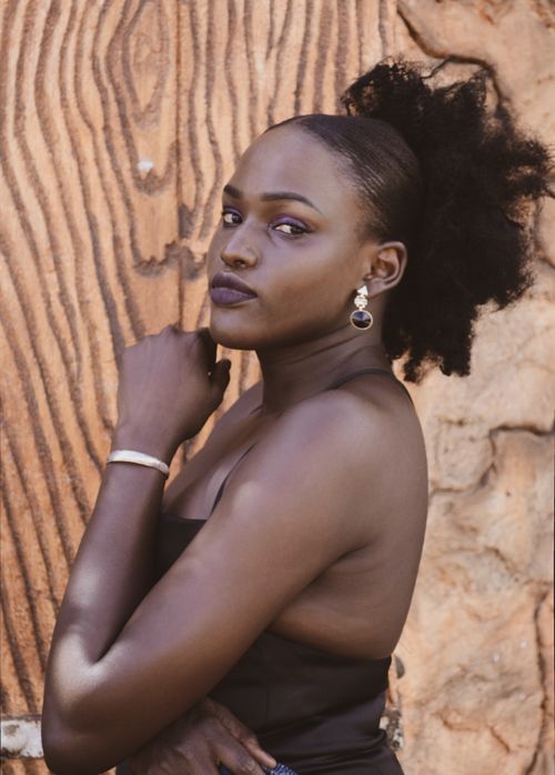 Free Stunning portrait of a woman with curly hair and earrings against a textured wall, exuding elegance. Stock Photo