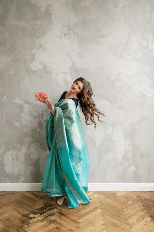 Free Woman in Teal Saree Dress Standing on Brown Wooden Floor Stock Photo