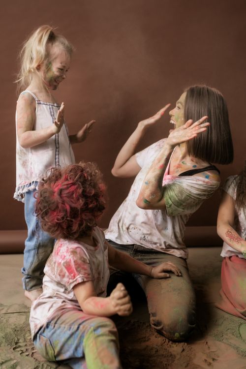 Free A joyful family moment as children and a woman play with colorful powders, sharing laughter and fun. Stock Photo