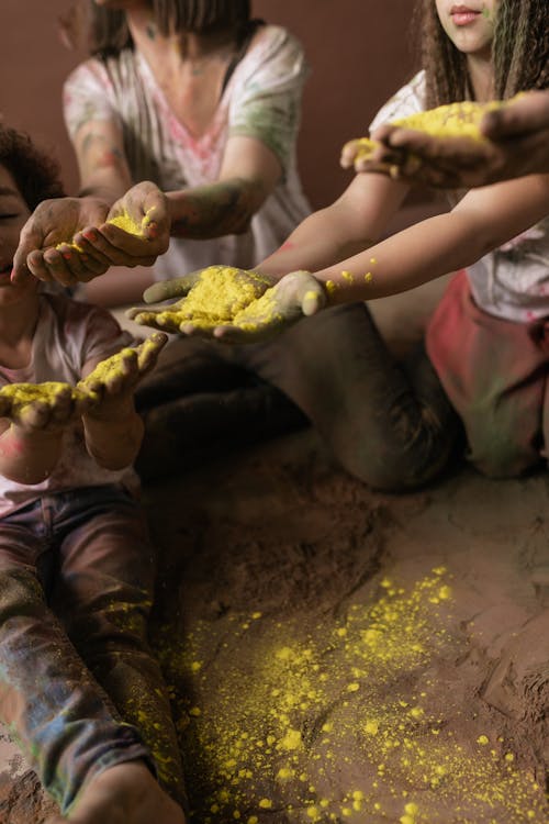 Free People Sitting Together with Palms in Yellow Holi Powder Stock Photo