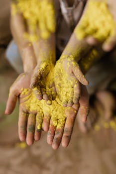 Close-up of hands covered in vibrant yellow Holi powder, symbolizing the celebration of tradition and color.