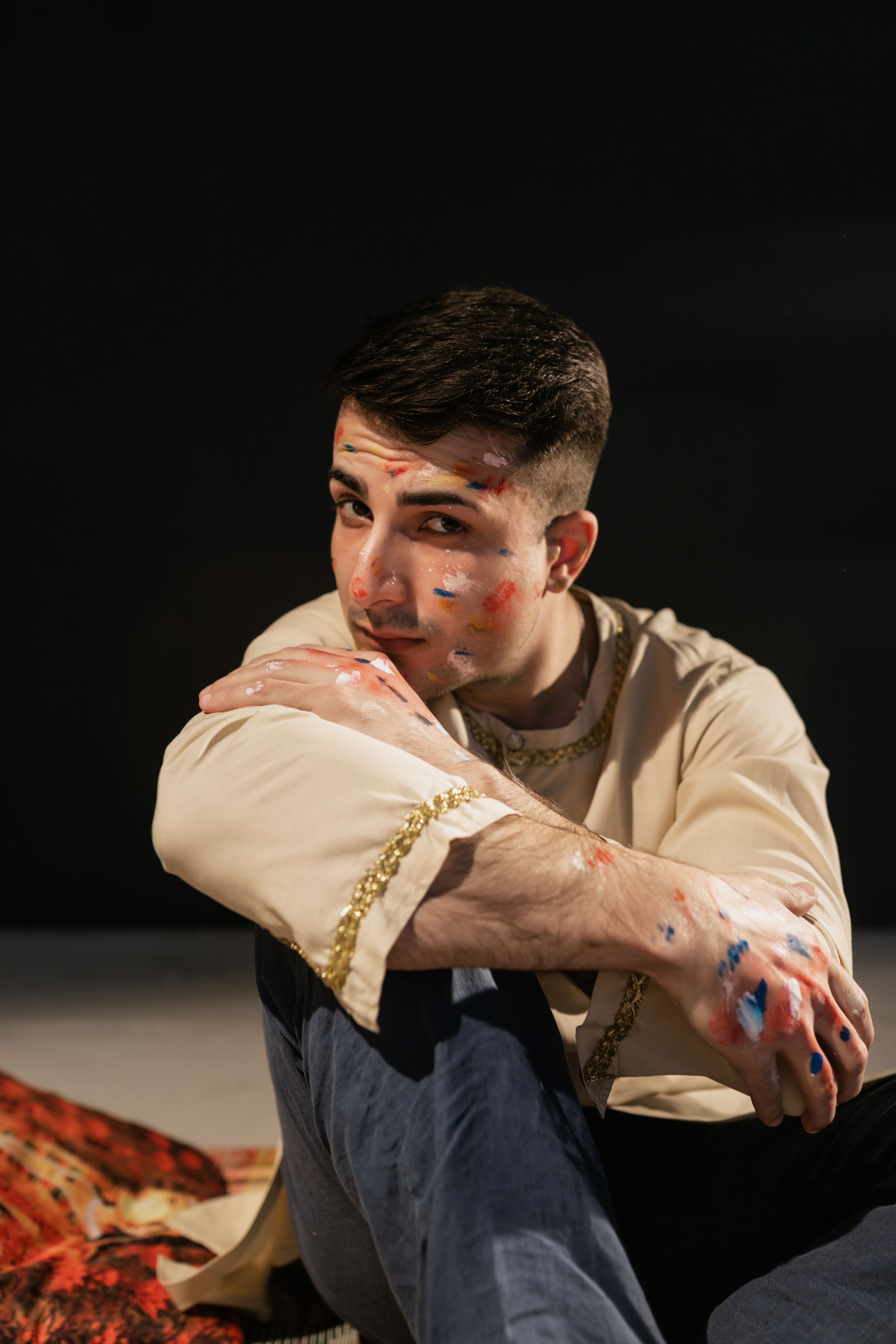 Artistic portrait of a man with body paint, captured in a studio environment.