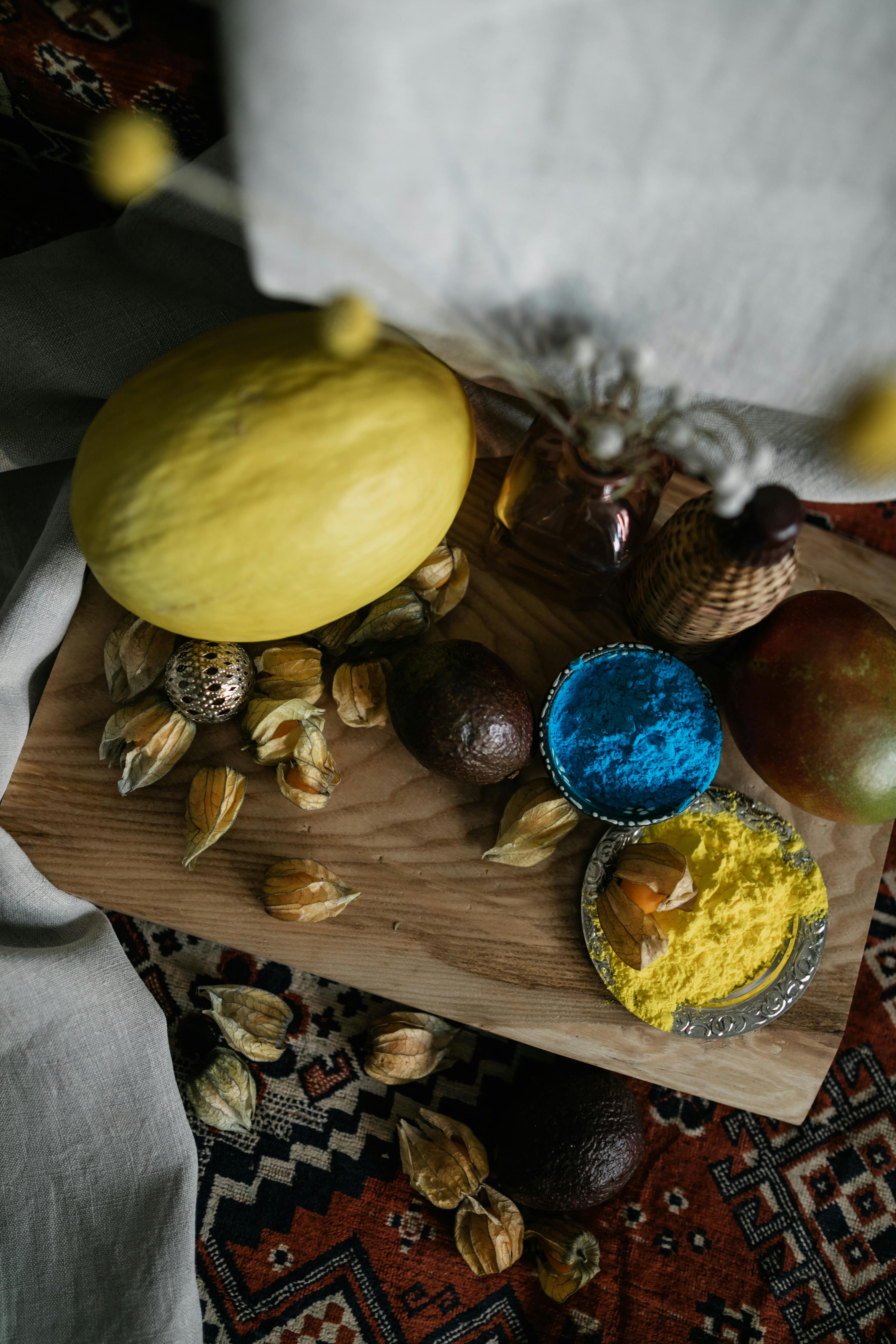A vibrant arrangement of fruits and colorful Holi powder on a wooden board.