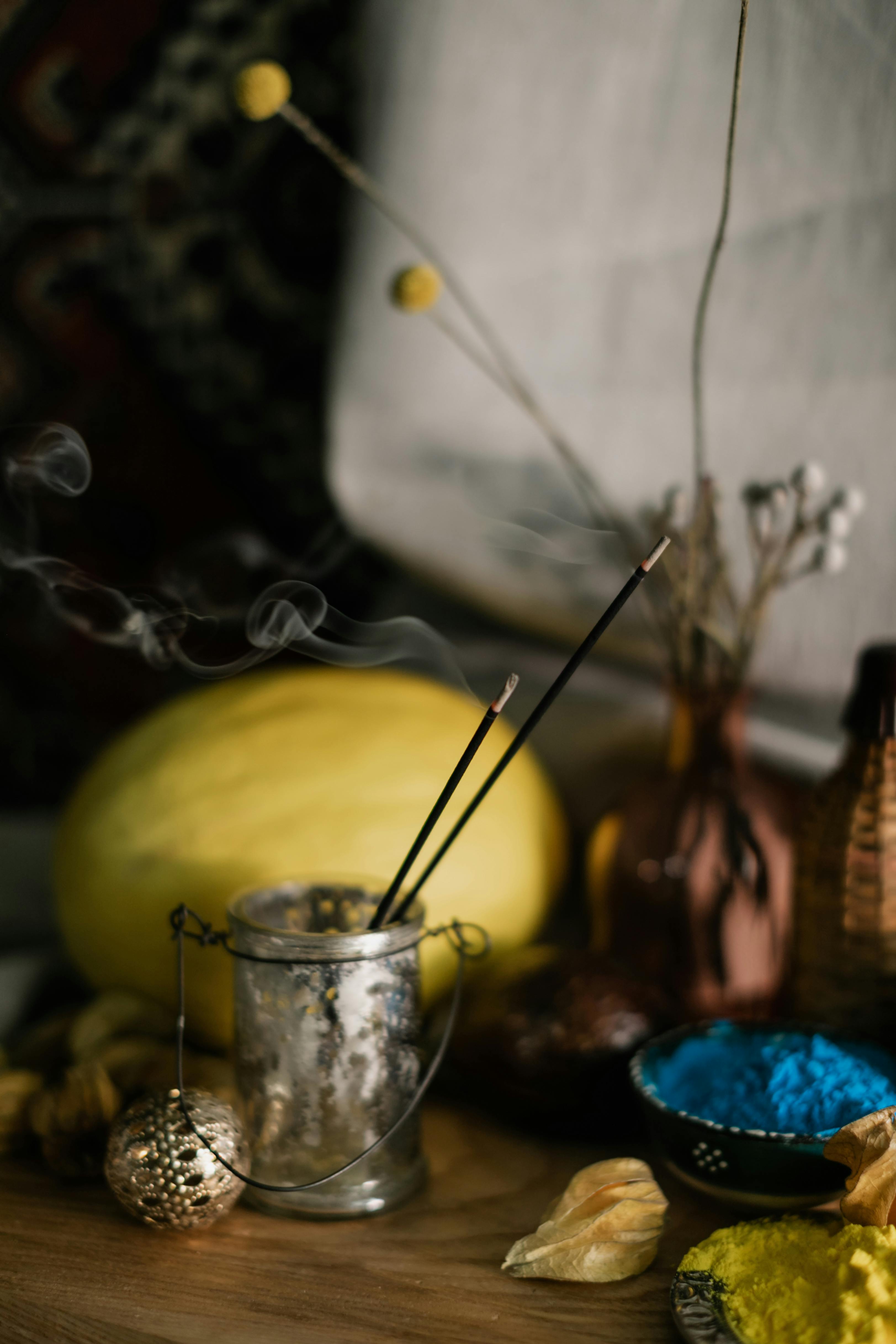 burning incense sticks in glass on table with decor