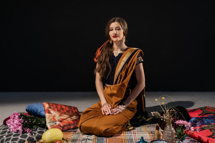 Woman In Accessories Resting On Ornamental Fabric On Black Background