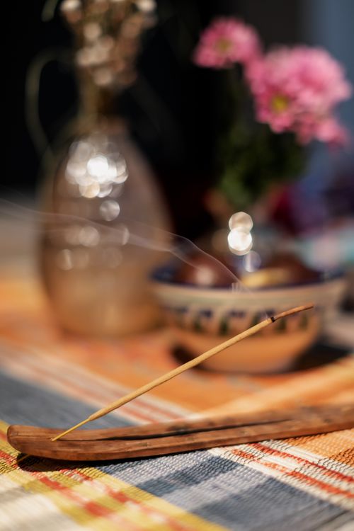 Free From above of burning traditional Indian Agarbatti incense stick placed on table near flower vase at home Stock Photo