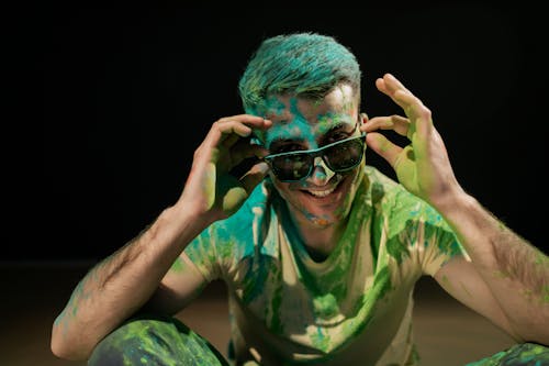 Man in Yellow Shirt with Green Powder on his Face