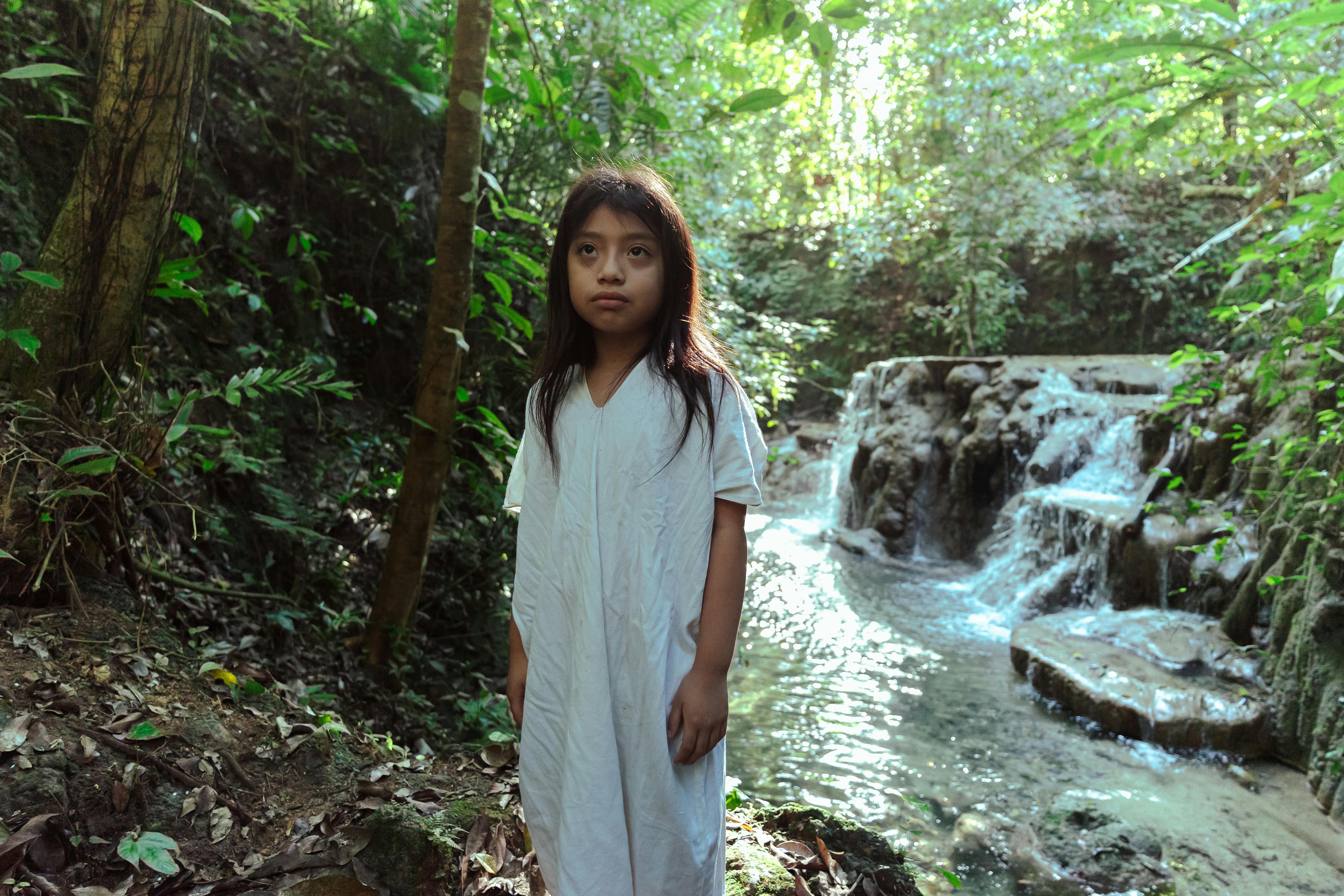 photo of girl standing beside flowing stream