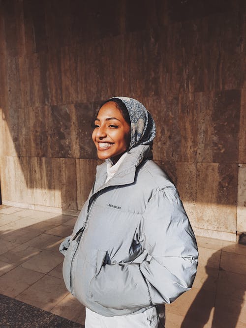 Smiling ethnic woman in hijab and outerwear