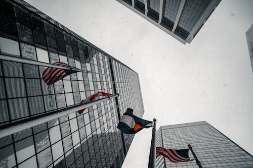 Low Angle Shot of Flags Swaying by the Wind Near Tall Buildings