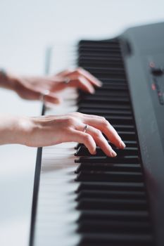 Artistic shot of hands playing piano keyboard. Soft focus, bright lighting.