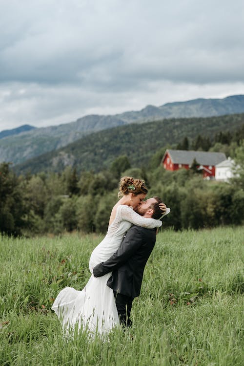 A Groom Carrying the Bride While Kissing on a Beautiful Nature