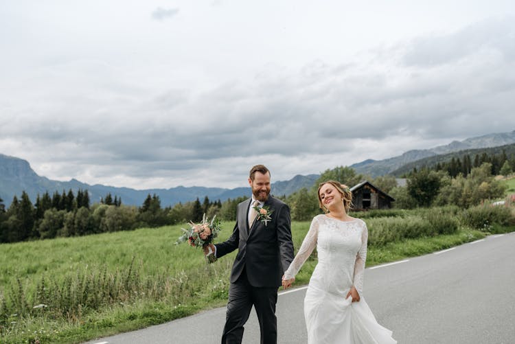 A Newlywed Couple Walking On The Road