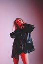 Serious woman in trendy outfit in studio with red lights