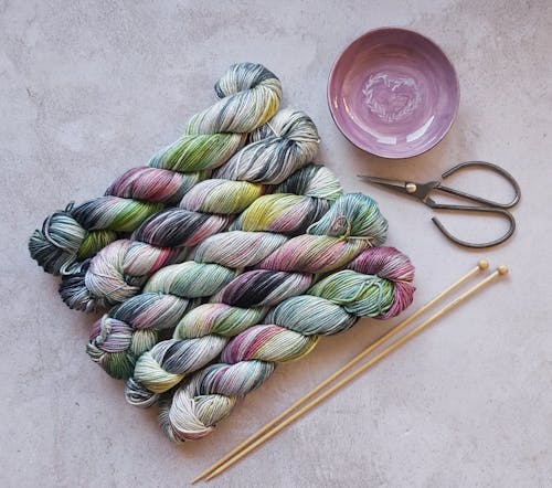 Dyed Yarn Beside Knitting Needles and Scissor 