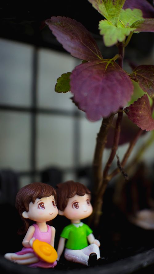 Free Small funny toys near fresh green and red leaves of plant on blurred background Stock Photo