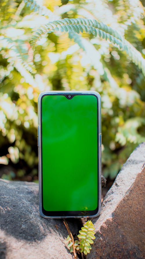 Free Convenient modern mobile phone with green chromakey on empty screen placed on rough stones on blurred background Stock Photo