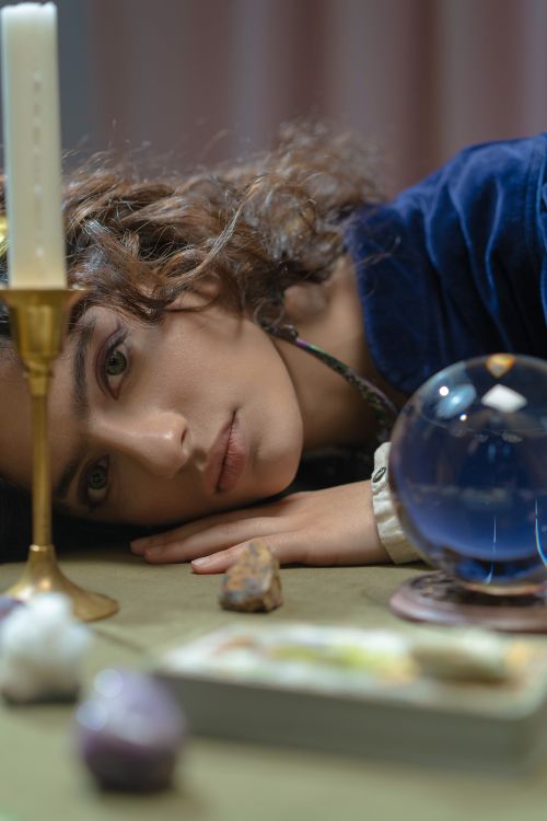 Free A woman lying beside a candle and crystal ball exuding a mystical and contemplative mood. Stock Photo