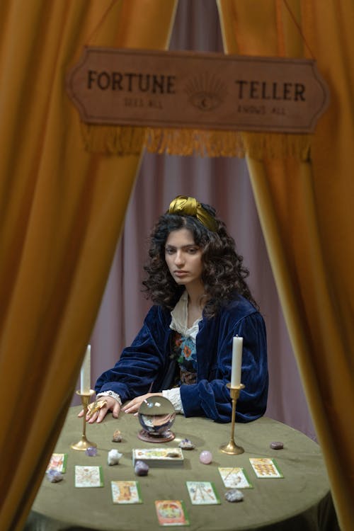 Free A Woman Sitting at a Table with Fortune Telling Paraphernalia Stock Photo