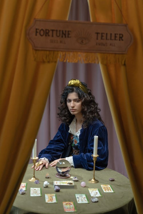 A Woman Sitting at a Table with Fortune Telling Paraphernalia