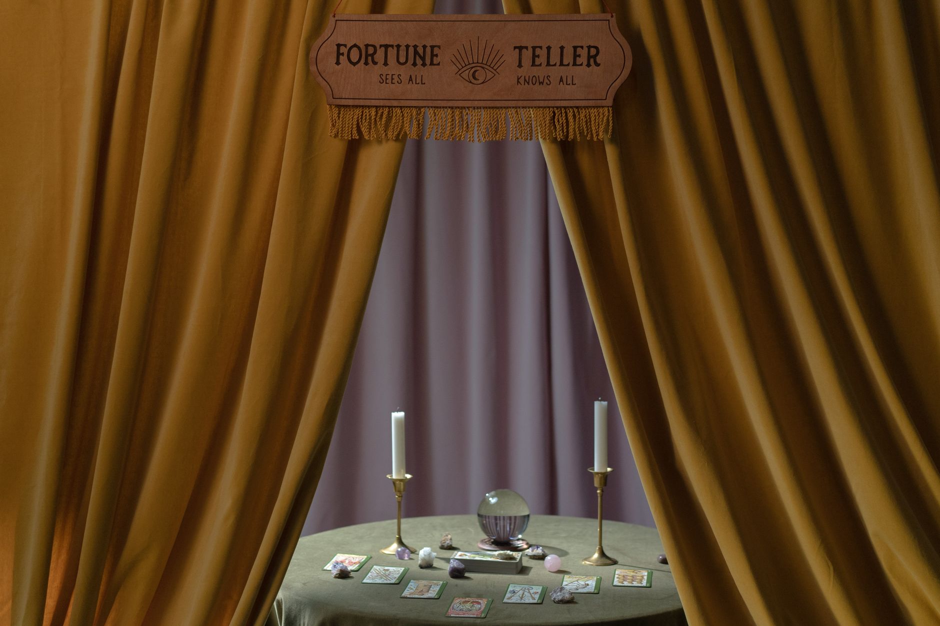 A mystical setup with a crystal ball, candles, tarot cards, and crystals, framed by curtains.