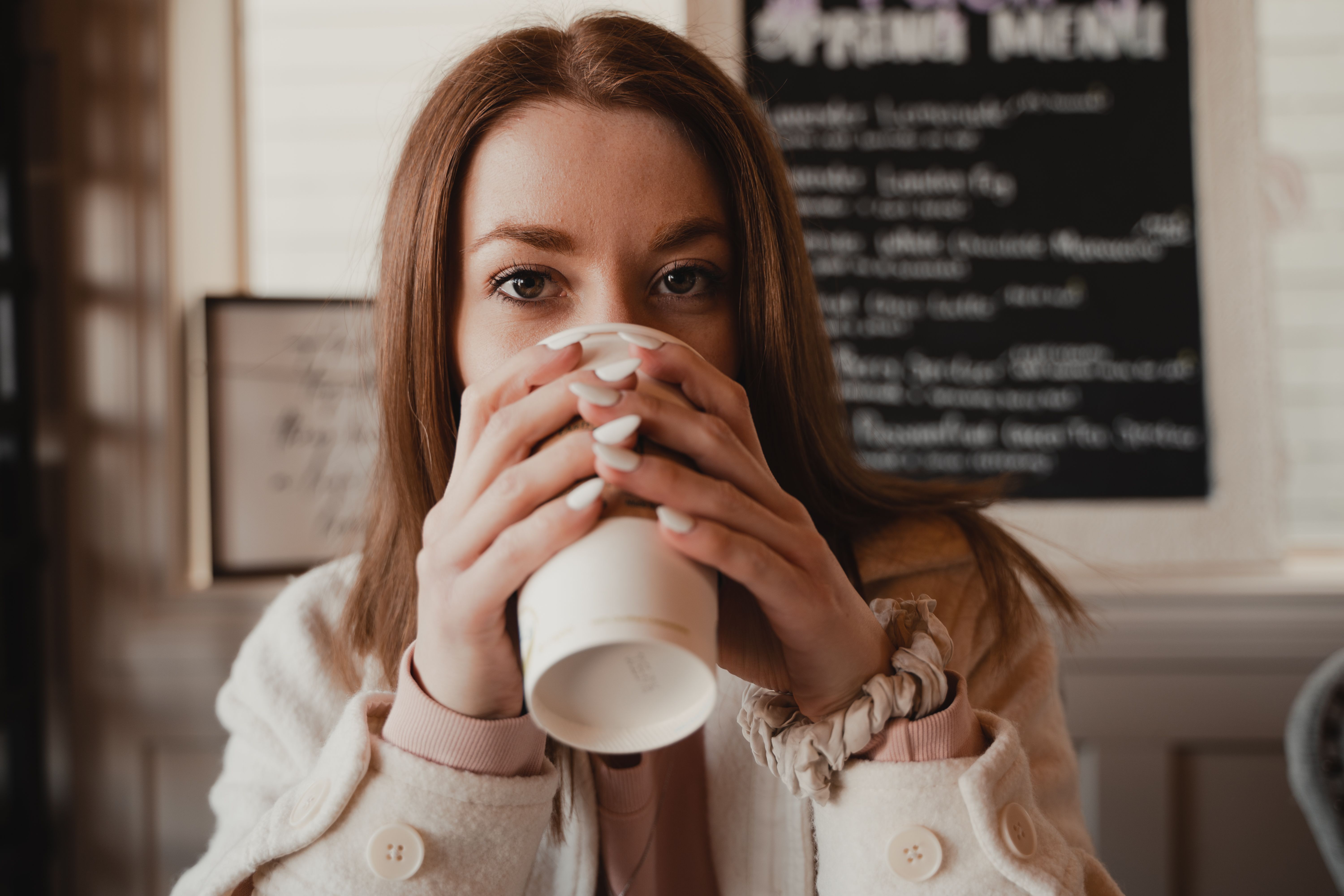 A Woman in Beige Coat Drinking Coffee from a Disposable Cup · Free ...