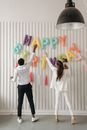 Woman in White Long Sleeve Shirt and Black Pants Standing Beside Balloons