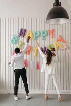 A family decorates with colorful balloons for a child's birthday indoors.