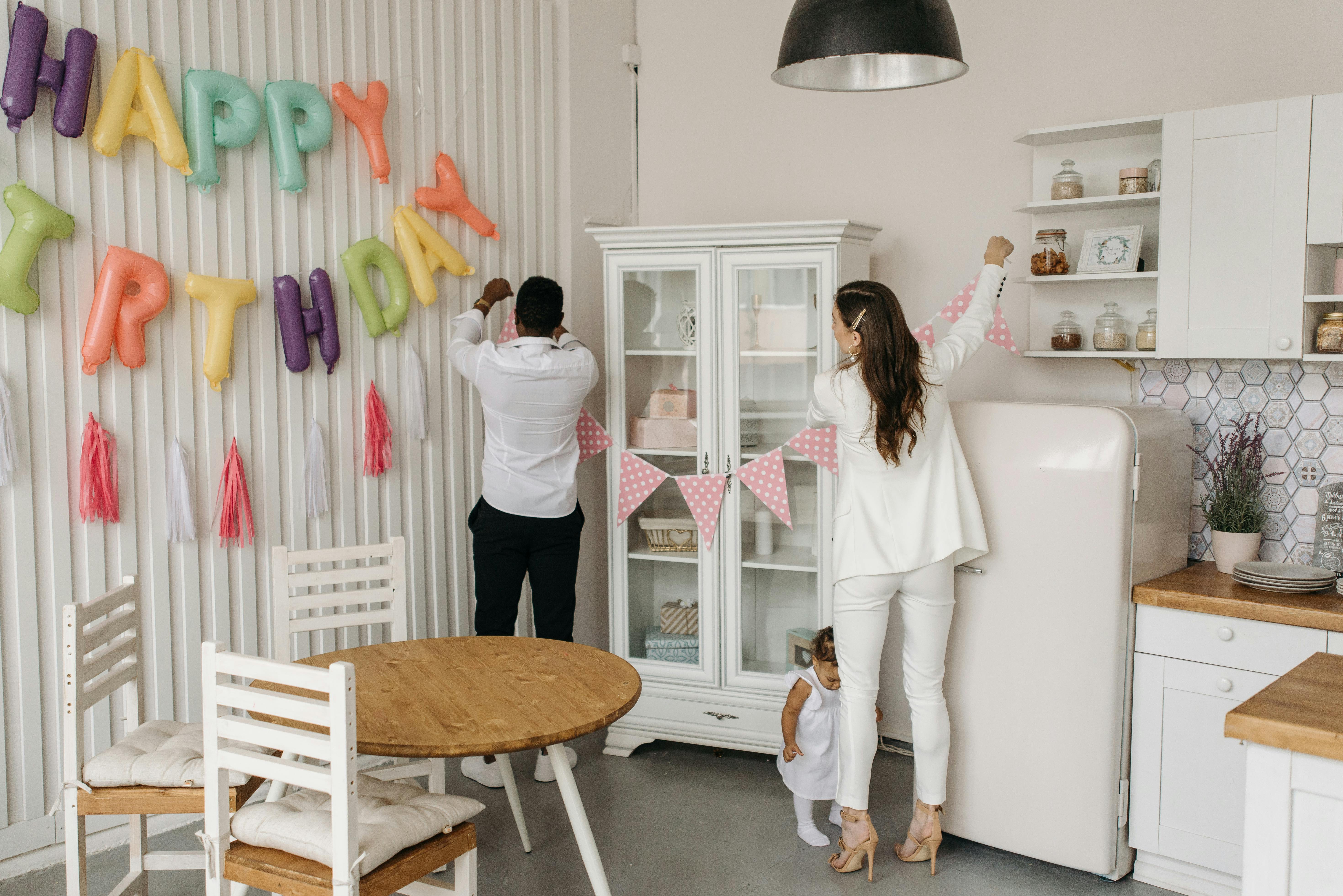 Parents decorating for their child's birthday at home with colorful balloons.