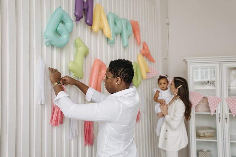 Family Putting Birthday Banner On The Wall