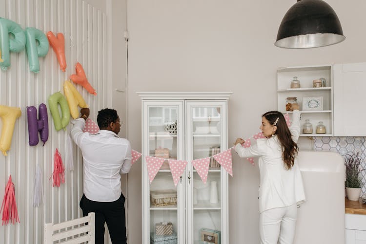 A Man And A Woman Hanging The Pennant Banners