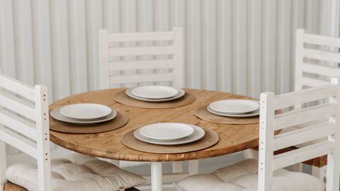 Cozy dining setup with wooden table, ceramic plates, and cushioned chairs in a minimalist style.