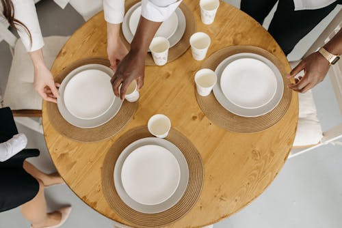 People Standing Near the Round Table with Ceramic Plates and Paper Cups
