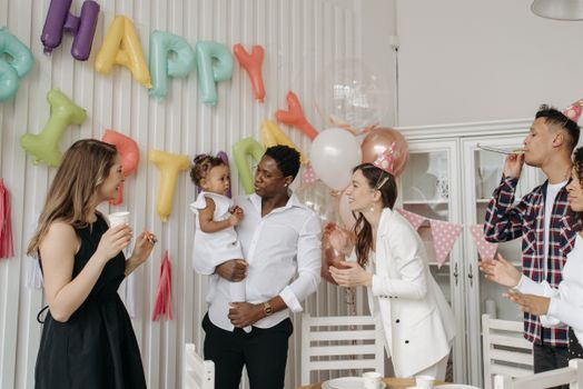 A diverse family celebrating a birthday with balloons and decorations indoors.