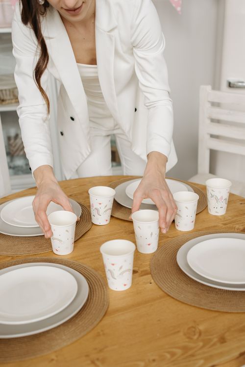 Free Woman arranging paper cups and plates on a wooden table for a celebration. Stock Photo