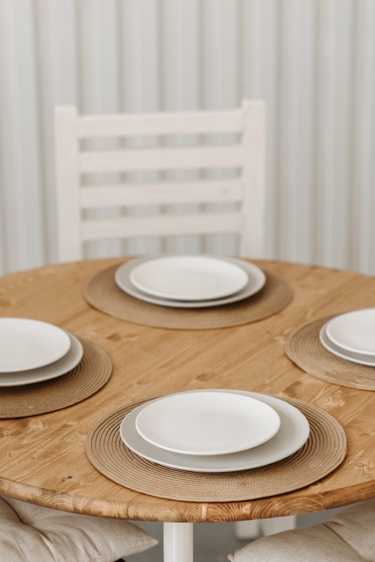 Four White Plates On Wooden Table