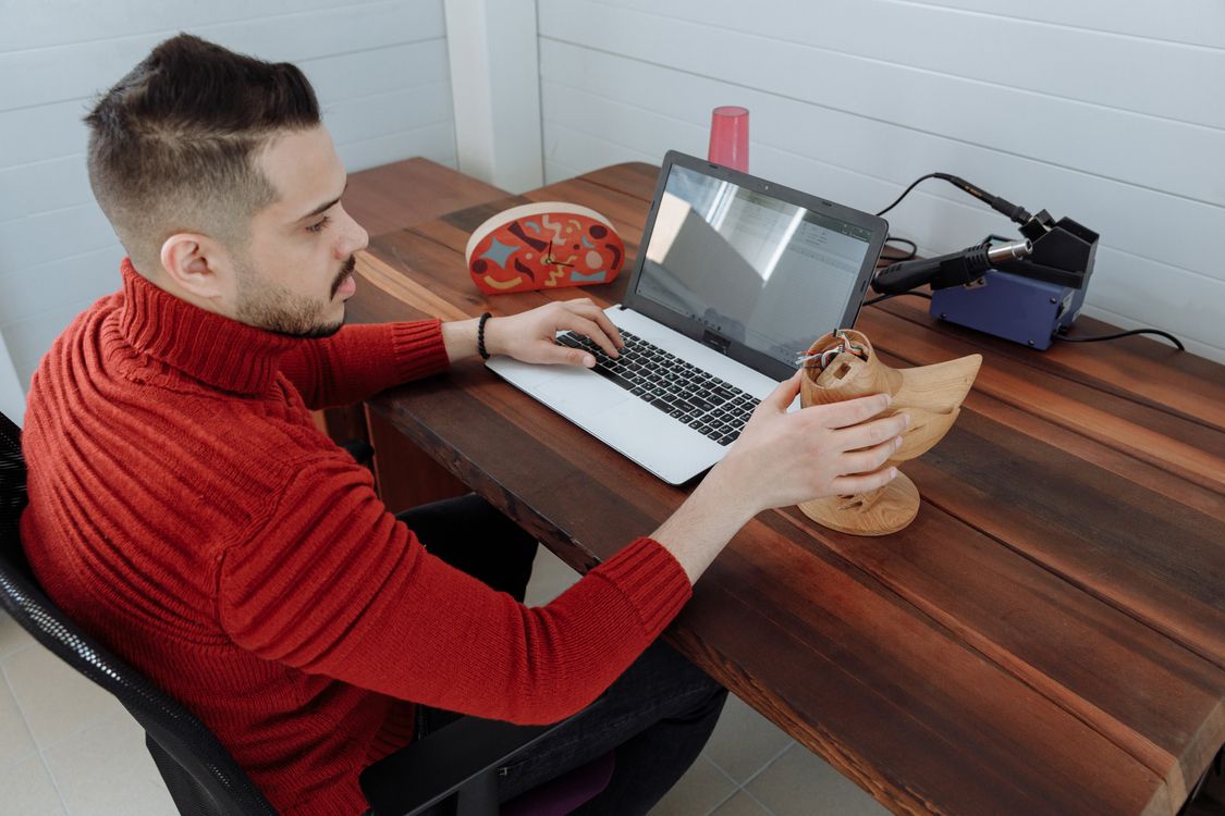 Engineer holding a 3D printed model while reviewing designs on a laptop