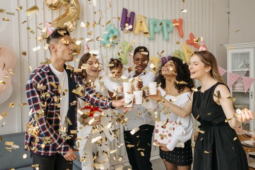 Free A lively indoor birthday party with friends celebrating with confetti and drinks in a decorated room. Stock Photo