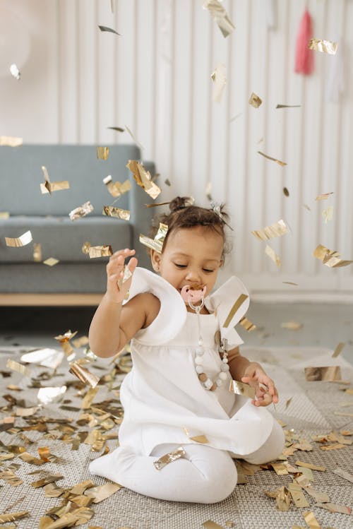 Child in White Dress Enjoying Confetti on Her Birthday