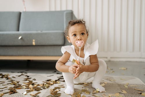 Child with a Pacifier Enjoy Picking Up Confetti on Her Birthday